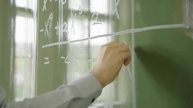 Close-up a Hand Writing Complex Algebra Polynomial on Green Chalkboard