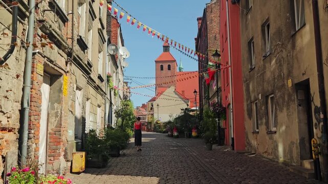 Slow motion scene of woman strolling through aged cobbled Grudziadz street
