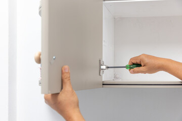 DIY home improvement: Adjusting a European cabinet hinge using a screwdriver.