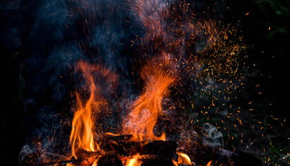 Fototapeta premium Abstract Orange Fire Flames with Blue Smoke and Floating Sparks on Dark Background, Dynamic Heat Energy and Dramatic Motion Texture