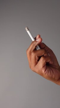 Person holding a cigarette in hand indoors