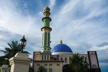 A mosque standing majestically against a beautiful blue cloud background