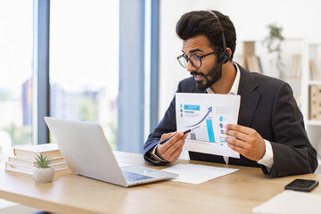 An Arab businessman presents a financial report during a video conference, using a laptop and headset
