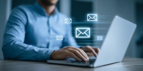 Fototapeta premium Person working on a laptop with digital email icons in a modern office