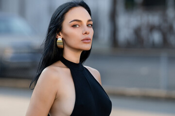 Portrait of Beautiful brunette woman posing on the street. Close-up Fashion woman portrait of young pretty trendy girl, summer street fashion. High fashion close up portrait of elegant woman outdoor.