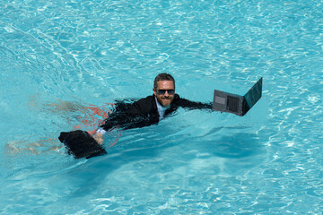 Crazy Business man in suit wit laptop in swimming pool. Crazy summer freelancer working in pool....