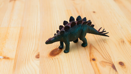 Dinosaur toy stegosaurus wooden table fun playtime scene indoor close-up imagination unleashed © M21Perfect