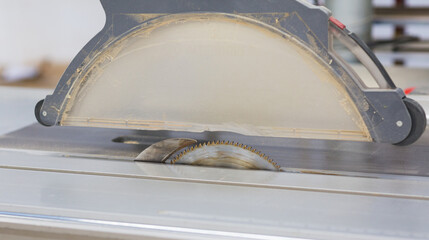 Close up of circular table saw blade cutting wood in workshop environment for carpentry, construction, woodworking safety and industrial manufacturing concepts