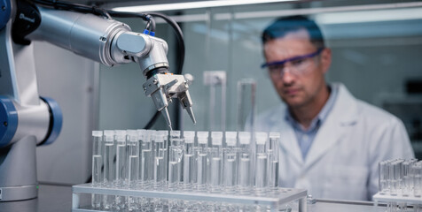 Focused scientist in laboratory using robot automation for research. This advanced machine and new technologies assist with water purification and analysis of test tube sample
