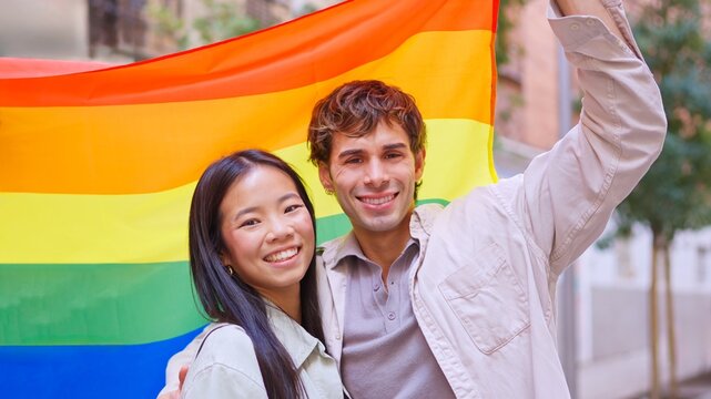 Diverse couple smiling celebrating rainbow flag inclusion - Powered by Adobe