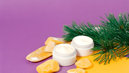 Anti Aging Christmas Skincare Two cosmetic cream jars with stones and pine branches on a colorful background.