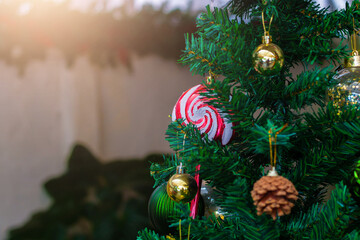 Close-up of a colorful lollipop ornament hanging on a Christmas tree with festive decorations, warm light, and holiday atmosphere.