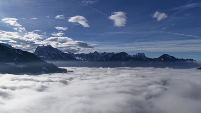 snowy Switzerland ridges rise above a vast rolling cloud ocean under a bright sky