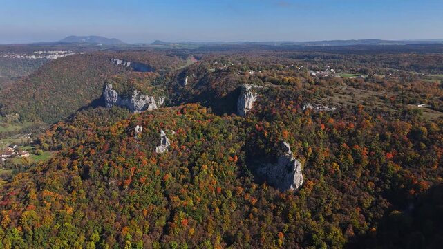 Aerial over mixed woodland and limestone escarpments in Giffre Valley near Cirque du Fer‑&agrave;‑Cheval nature reserve, with rocky outcrops and canopy of beech and conifers in autumn foliage