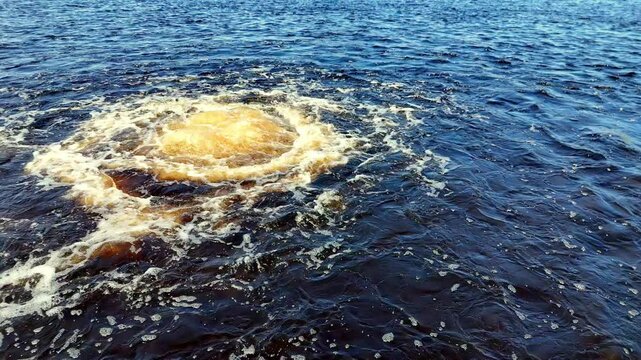 Low-angle view of a turbulent, dark-blue Baltic Sea during Autumn, with a central, massive, yellowish methane gas eruption plume