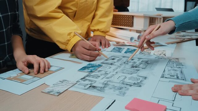 A diverse group of architects and designers collaborating in a modern workspace, examining detailed sketches and blueprints, embodying creativity and teamwork. SACTR