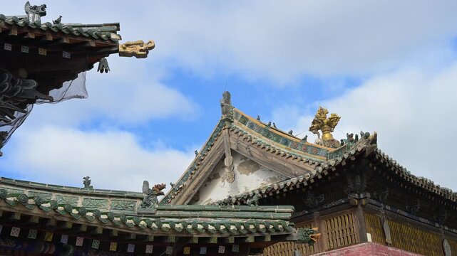 Wide view of the temple complex at Erdene Zuu Monastery, Mongolia. Multiple ancient structures with ornate green tiled roofs and red walls showcase the scale of this historic Buddhist site.