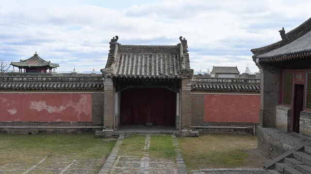 Wide view of the temple complex at Erdene Zuu Monastery, Mongolia. Multiple ancient structures with ornate green tiled roofs and red walls showcase the scale of this historic Buddhist site.