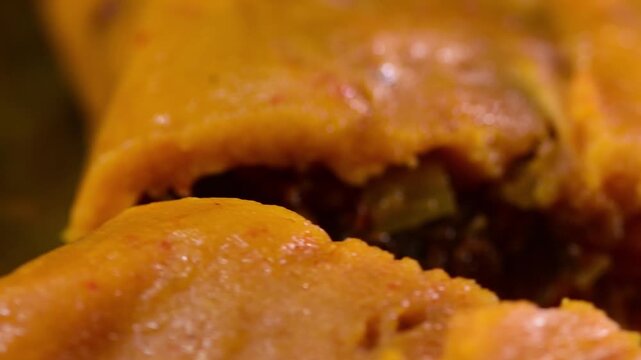 Slow motion, detailed view of a freshly cooked, traditional Venezuelan hallaca with savory stew filling, spinning on its green banana leaf wrapper