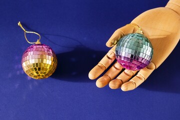 Wooden Hand with Festive Glittery Disco Balls Decorations on Blue Background. Christmas Holiday...