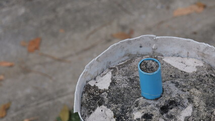 Close-Up View of a Blue Pipe Cap Resting on Wet Concrete Surface with Leaves