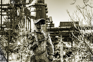 In der monochromen Härte des Bildes steht die Statue des Bergmanns als Denkmal der Schwerarbeit,...