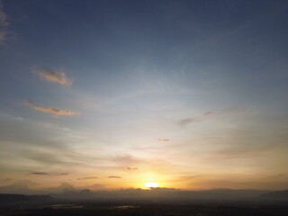 Fototapeta premium Beautiful sunset sky with soft clouds over distant landscape, warm golden tones creating a calm and atmospheric natural background.