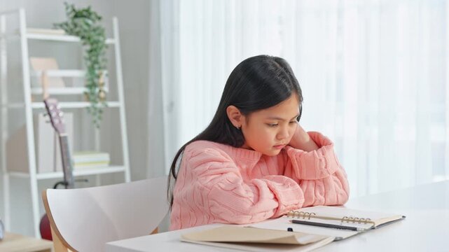 Asian young girl struggling with homework while grandmother helping. 