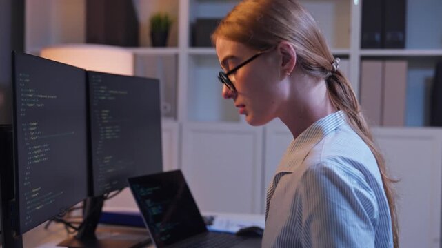 Caucasian young female software engineer working at night in the office