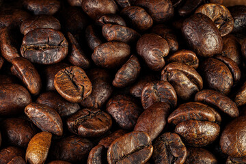 Close-up view of roasted coffee beans with rich brown tones and detailed surface texture. Dark background, premium food texture.