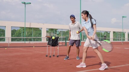 Asian sportswoman practicing tennis with trainer on outdoor clay court. - Powered by Adobe