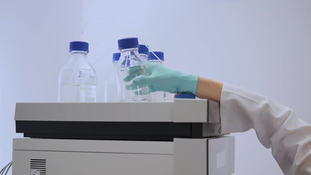 Close up lab worker change mobile phase of HPLC system.