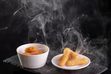 Hot crispy chicken nuggets with steam on slate plate, dark background
