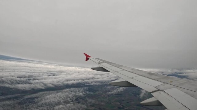 Airplane wing view flying over cloudy landscape during the day