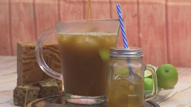 Pouring Fresh Sugar Cane and Lime Juice into Glass Pitcher