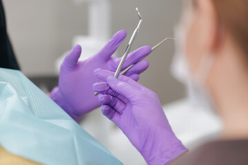 Female dentist in purple gloves holding dental tools in clinic setting