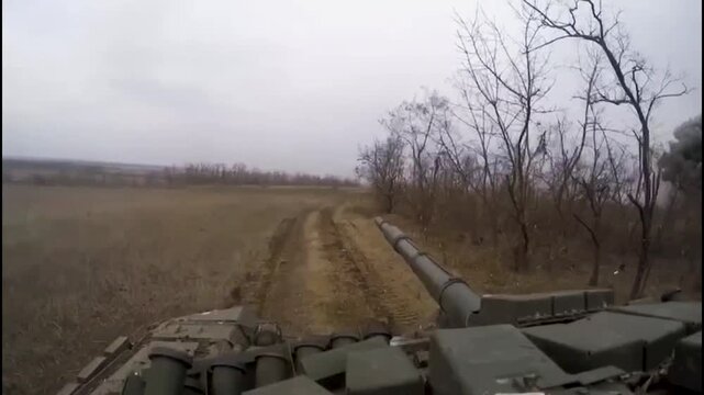 An armored battle tank drives backwards, fire flashes from explosions can be seen on the side in front. The tank dodges damage. A tank during combat work on the battlefield. A real war.