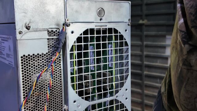 Handheld close-up of a technician servicing high-stakes Bitcoin mining hardware, emphasizing the intricate and dirty nature of the work