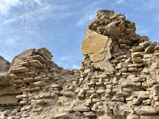 Close-up of severely crumbling ancient brick ruins under a blue sky.