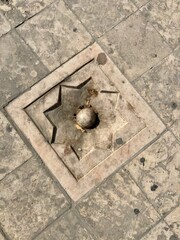 Carved stone paver with an eight-pointed star design on a floor.