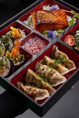 Bento box with gyoza, sushi, salmon and tempura