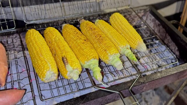 4K close up of golden corn and sweet potatoes roasting on a charcoal grill showing detailed texture warm tones and a rustic outdoor cooking atmosphere.
