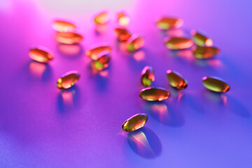 Colorful capsules vitamin omega 3 Fish oil on purple surface with vibrant lighting