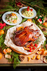 A carefully arranged holiday table showcases a succulent duck with vibrant sides and festive decor
