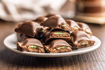 Chocolate bar with pistachios cream on plate on wooden table.
