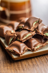 Chocolate bar with pistachios cream on plate on wooden table.