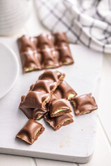 Chocolate bar with pistachios cream on white table.