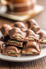 Chocolate bar with pistachios cream on plate on wooden table.