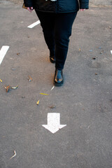 Woman standing near a white arrow painted on the asphalt