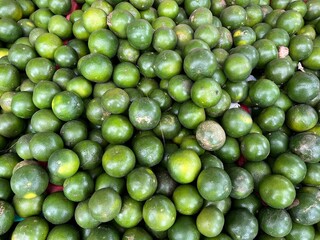A Large Pile of Fresh Green Oranges or Limes Displayed for Sale at a Local Fruit Market